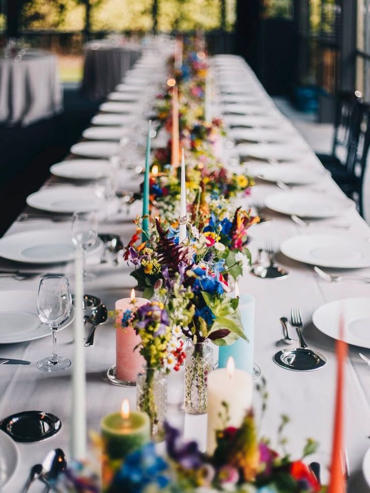 Lange gedekte tafel met kaarsen en veldbloemen